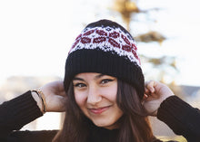 Load image into Gallery viewer, Woman wearing a black knit beanie with a pattern, smiling outdoors.